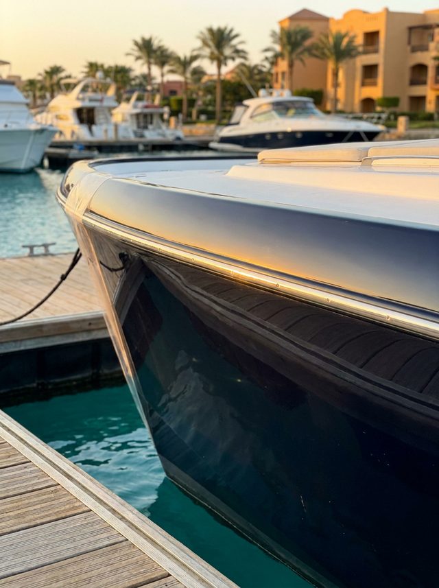 A sleek dark navy yacht hull in side profile at an El Gouna marina at golden hour
